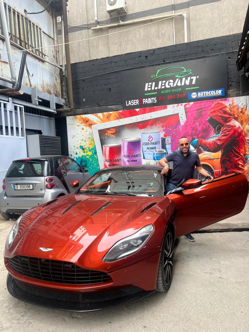 Orange Aston Martin at the body shop with Raffi